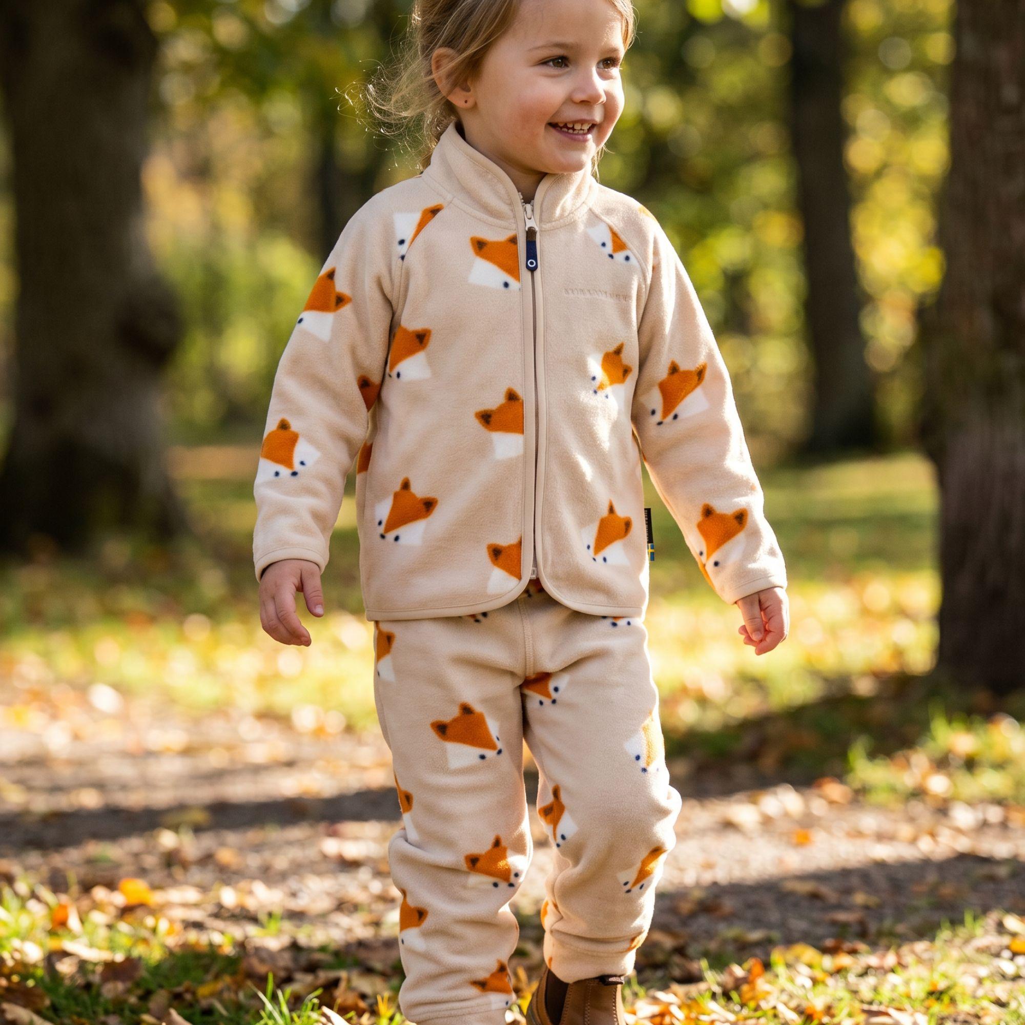 Beige fleeceset med rävtryck i mjuk fleece på ett barn i en höstpark från Geggamoja.