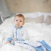 Blåmönstrad Geggamoja pyjamas i mjuk bambu med klövermönster på en baby i en säng.