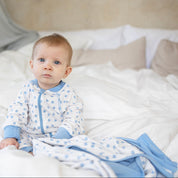 Blå klövermönstrad babyfilt i mjuk bambu från Geggamoja i en mysig sängmiljö.
