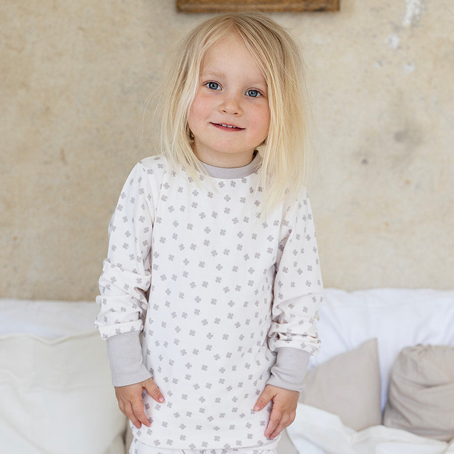 Beige tvådelad pyjamas i mjuk bambu med klövermönster på ett barn från Geggamoja.